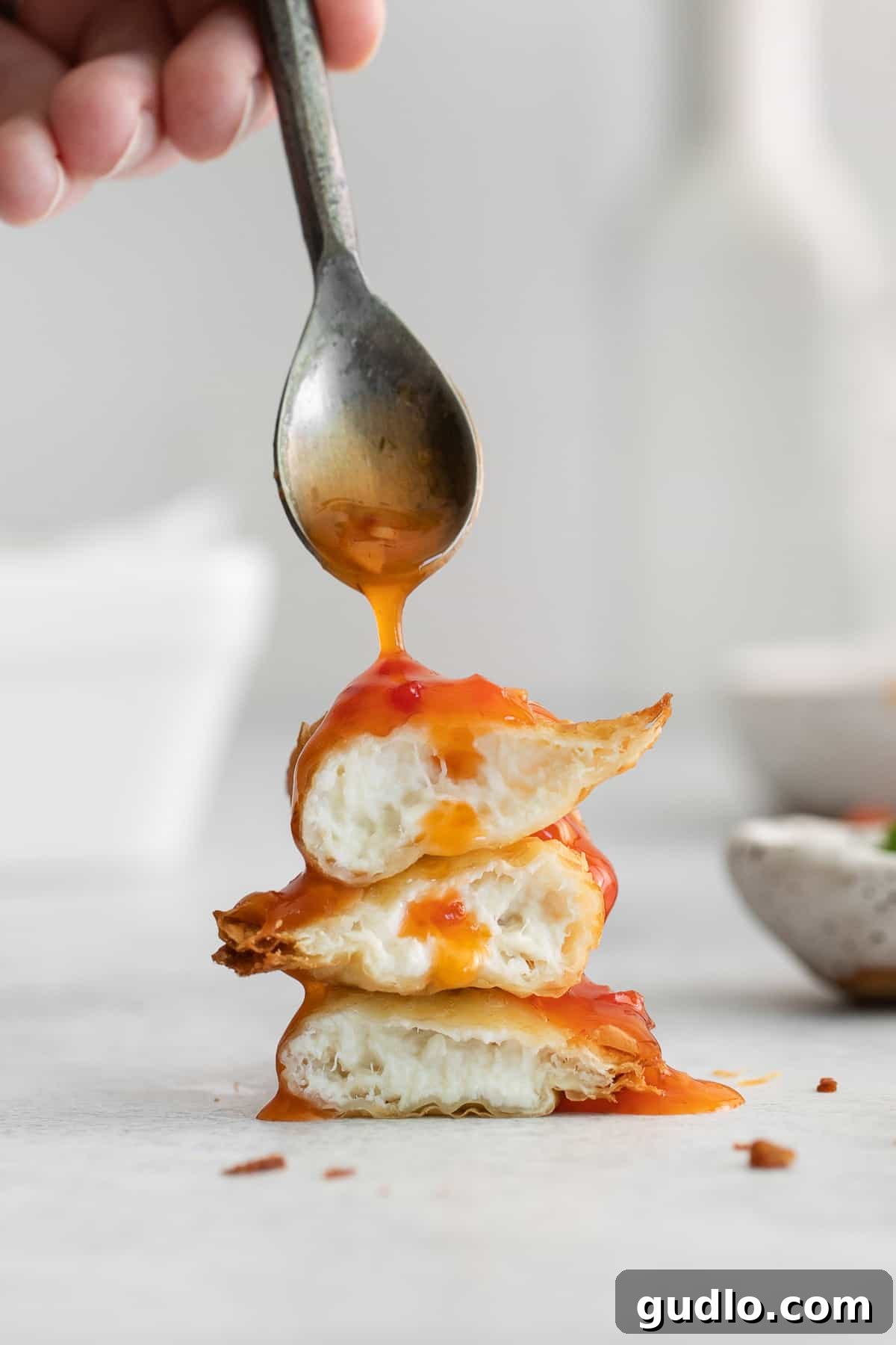 Crispy Crab Rangoons with Sweet and Sour Sauce Slathering golden-brown crab rangoons with sweet and sour sauce, showcasing their crispy texture and inviting aroma.