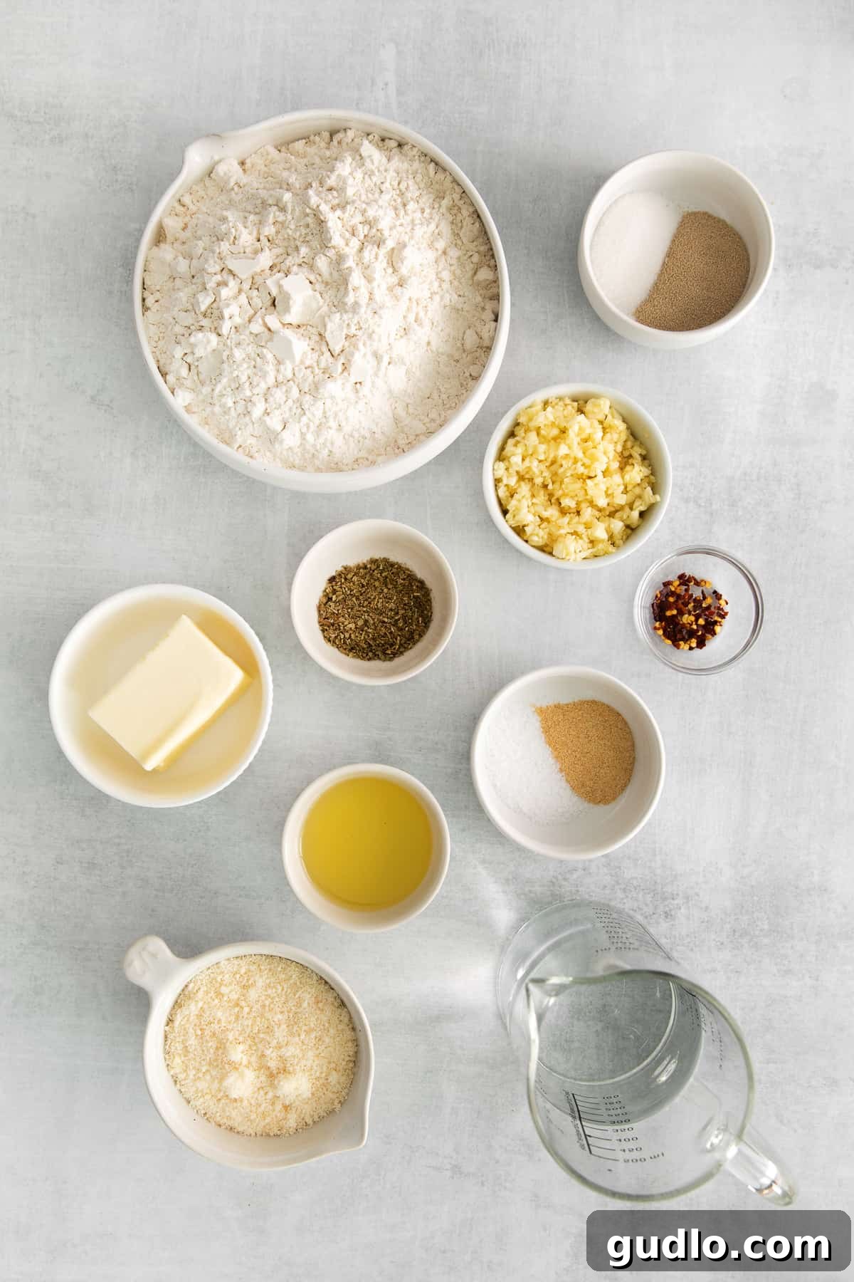 A collection of measured ingredients for Parmesan garlic knots, neatly presented in bowls, ready for mixing.