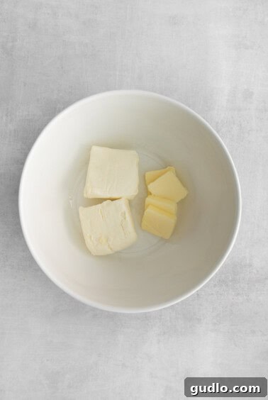 Cream cheese and butter in a bowl, being mixed together to a creamy consistency.