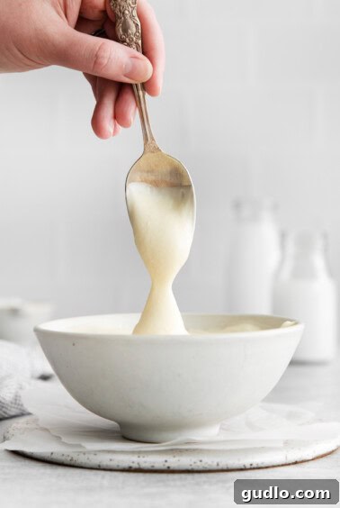 The frosting mixture in a bowl after adding powdered sugar, appearing smooth and thick.