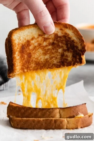 A finished grilled cheese with mayo, sliced in half, ready to be enjoyed.