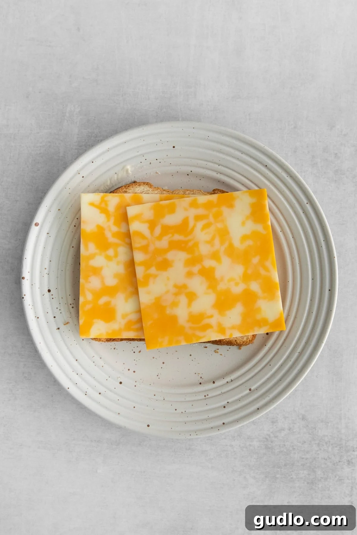 Layering the Cheese for Optimal Melt Two generous slices of Colby Jack cheese carefully placed on a slice of bread, forming the base of the grilled cheese sandwich.