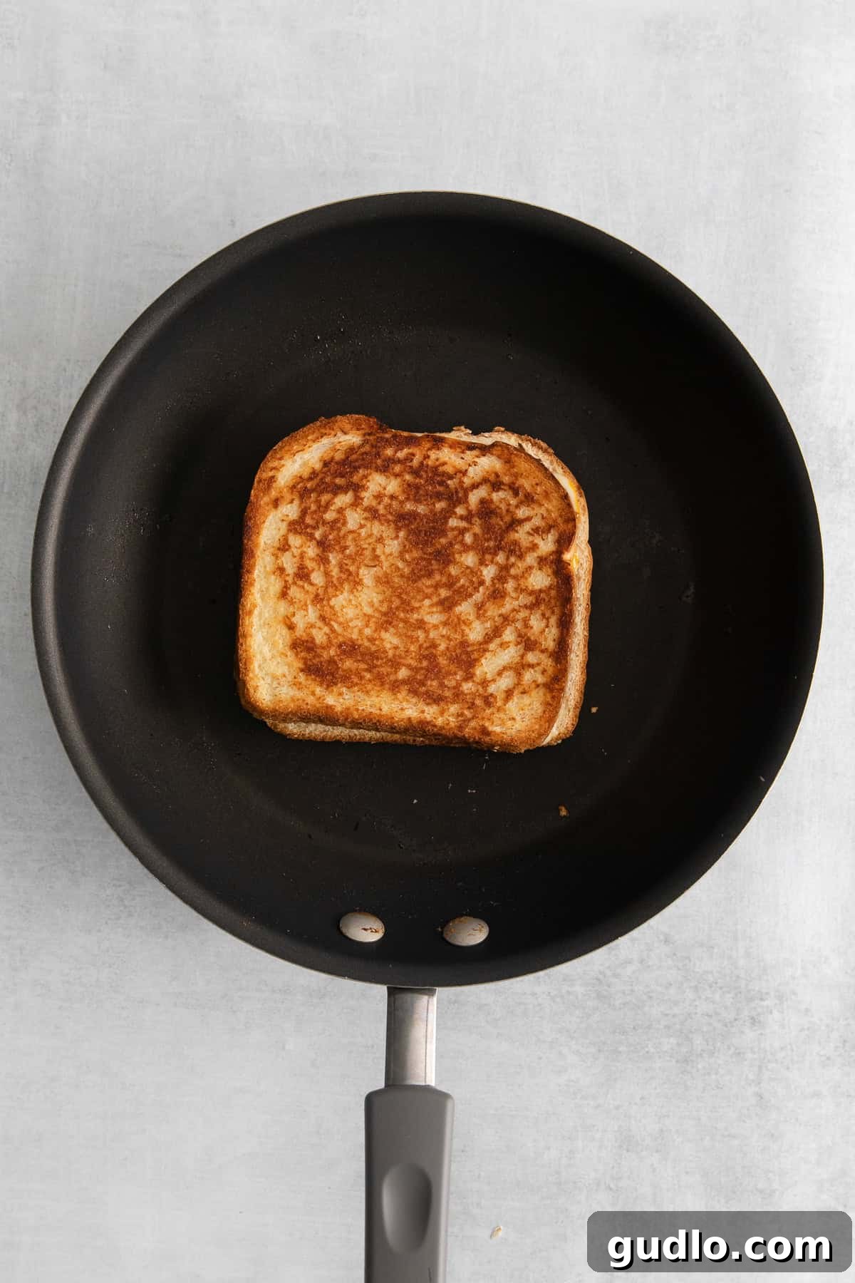Sizzling Perfection: Mayo Grilled Cheese in the Pan Grilled cheese with mayo cooking in a hot skillet, achieving a perfect golden-brown and crispy crust. The edges are visibly browning.