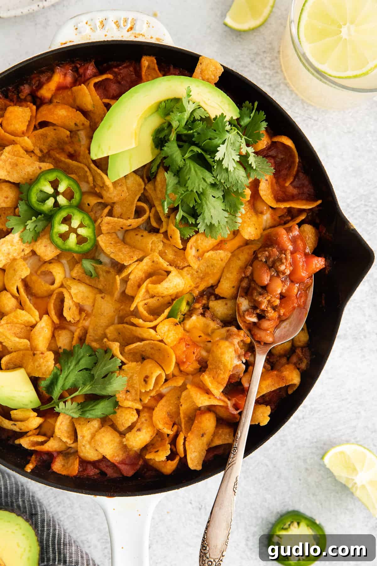 Delicious Cheesy Frito Taco Skillet: Perfect for Family Dinners & Parties Vibrant Cheesy Frito Taco Skillet generously topped with creamy sliced avocado and a sprinkle of fresh jalapeno, ready to be served.