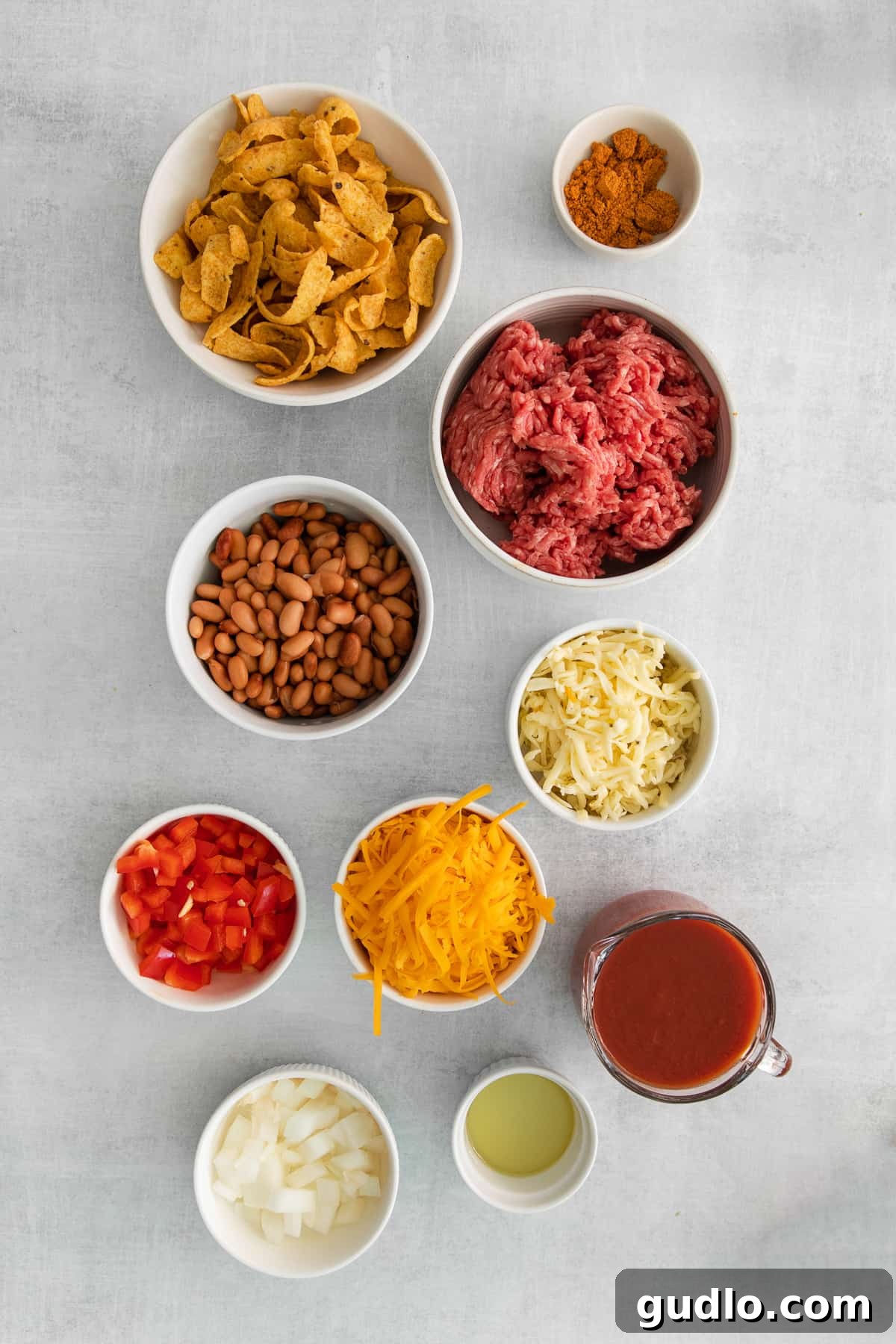 Fresh Ingredients for the Perfect Cheesy Frito Taco Skillet Assortment of fresh ingredients for a cheesy frito taco skillet, neatly arranged in small bowls on a wooden surface.