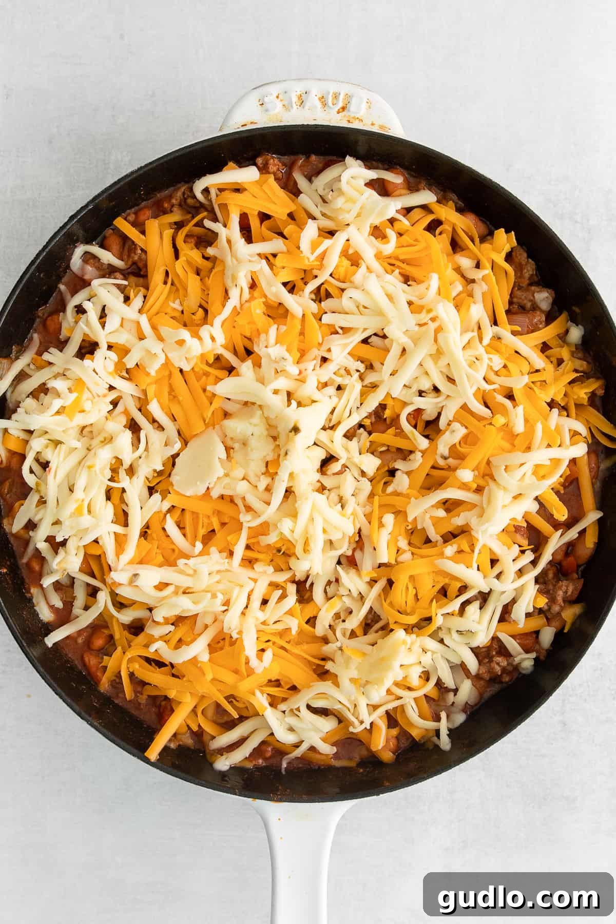Melted Cheese Perfection on a Cheesy Frito Taco Skillet Close-up of the Cheesy Frito Taco Skillet, showcasing a generous layer of perfectly melted shredded cheddar and pepper jack cheese bubbling over the savory filling.