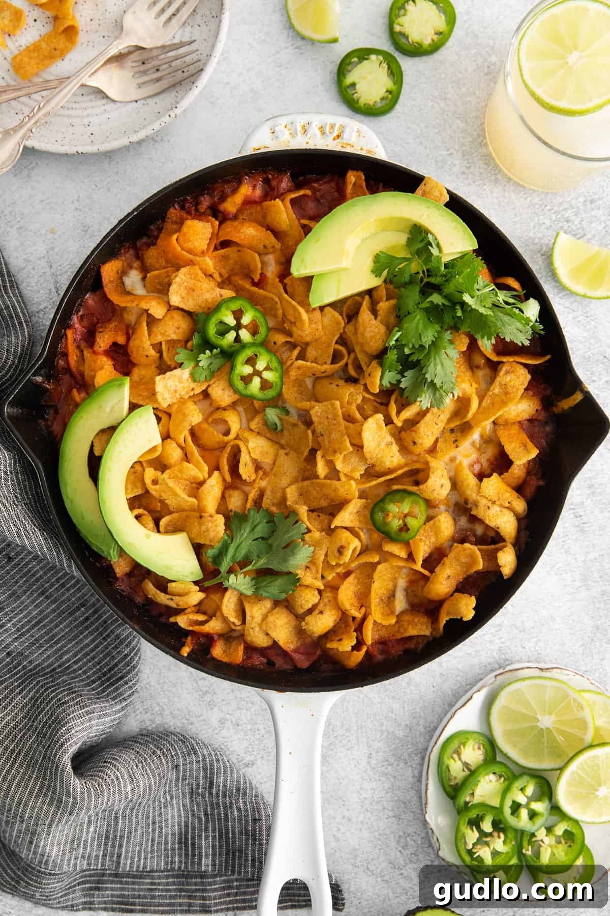 Garnished Cheesy Frito Taco Skillet with Avocado and Cilantro A generous serving of Cheesy Frito Taco Skillet, adorned with fresh, vibrant sliced avocado and a delicate sprinkle of cilantro, showcasing a perfect balance of flavors and textures.