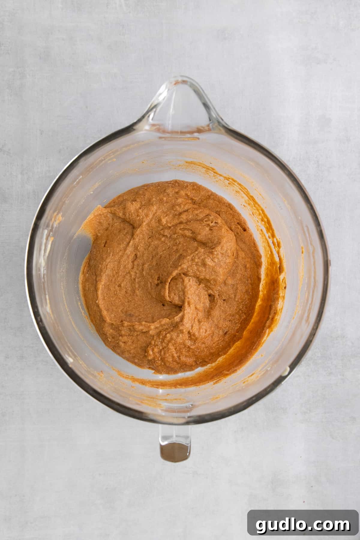 A glass bowl filled with the smooth, orange-hued pumpkin bar batter, showcasing its ready-to-bake consistency.