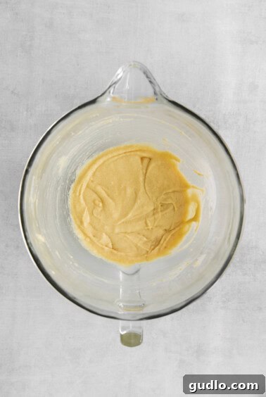 A glass bowl filled with a yellow batter, indicating the creaming of butter and sugars.