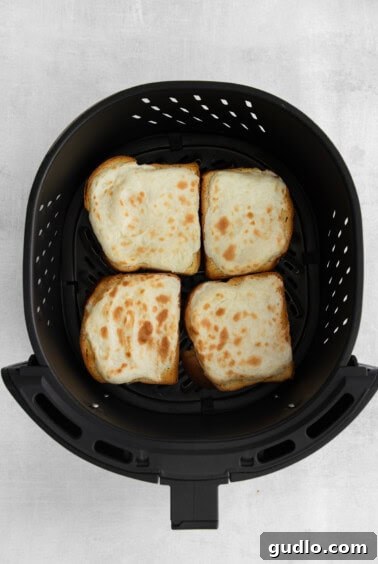 Decadent Strawberry Cheesecake French Toast 13 A black air fryer basket containing several slices of strawberry cheesecake French toast cooking.