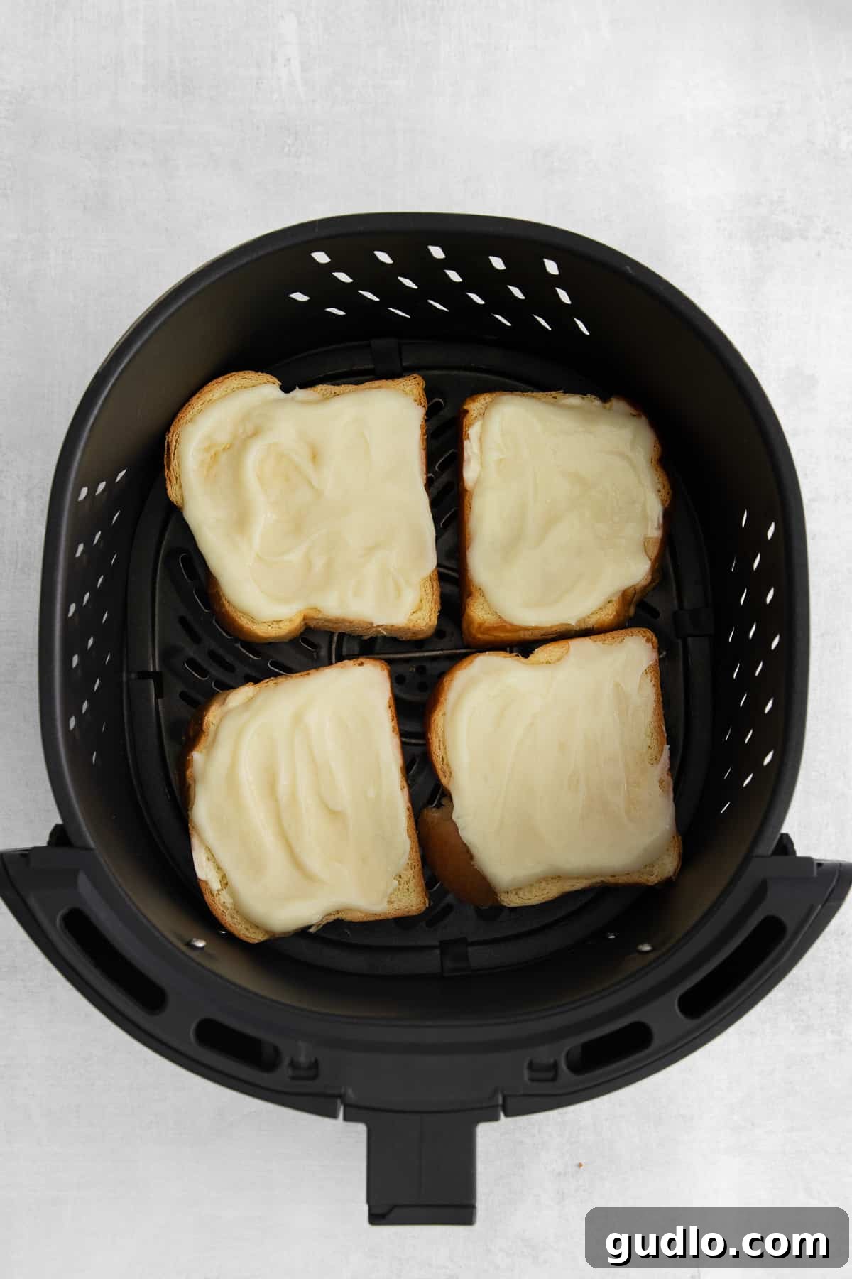 Decadent Strawberry Cheesecake French Toast 6 Strawberry cheesecake french toast slices cooking to golden perfection in an air fryer basket.