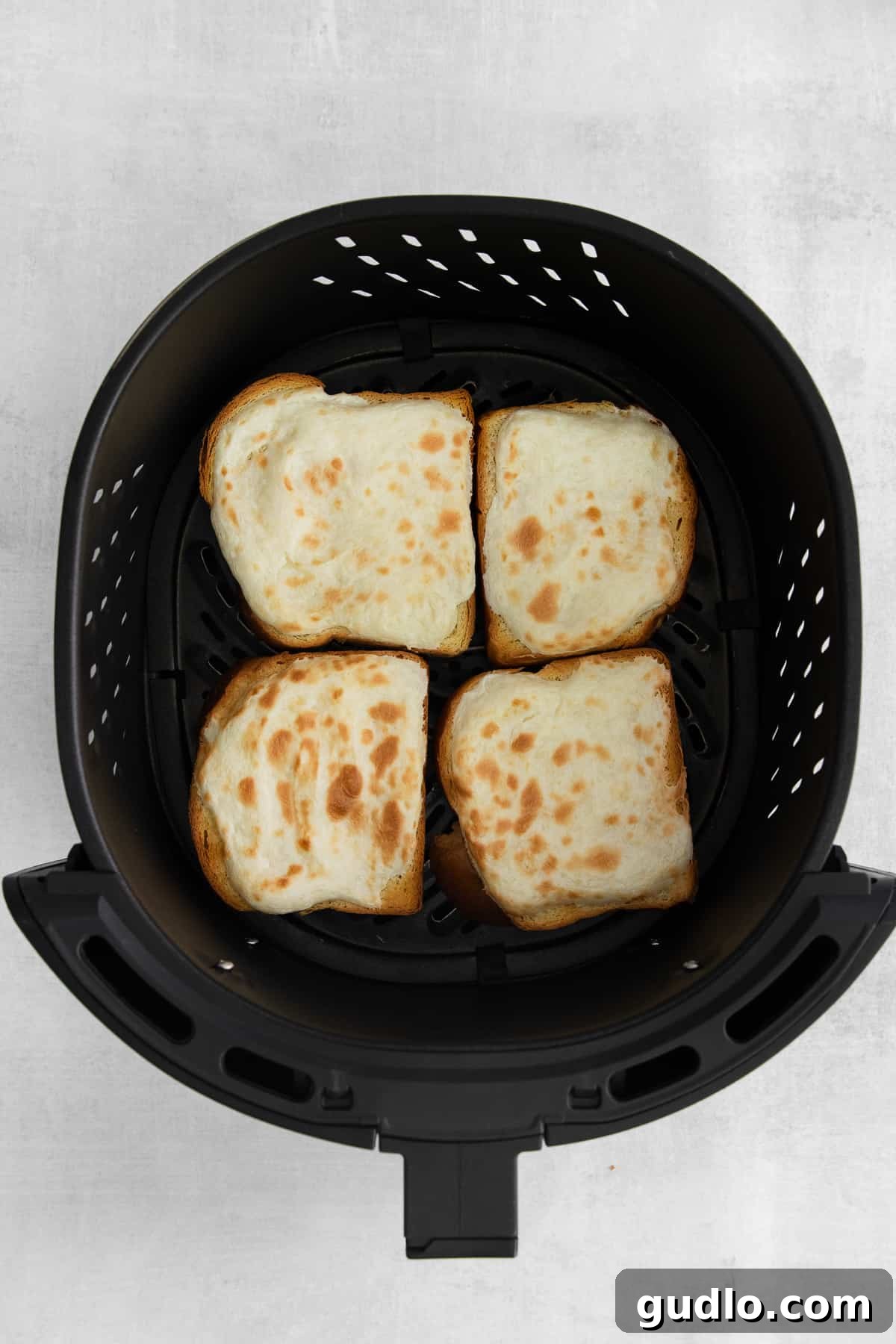 Decadent Strawberry Cheesecake French Toast 7 Close-up of several strawberry cheesecake french toast slices, beautifully golden and warm, arranged within an air fryer.
