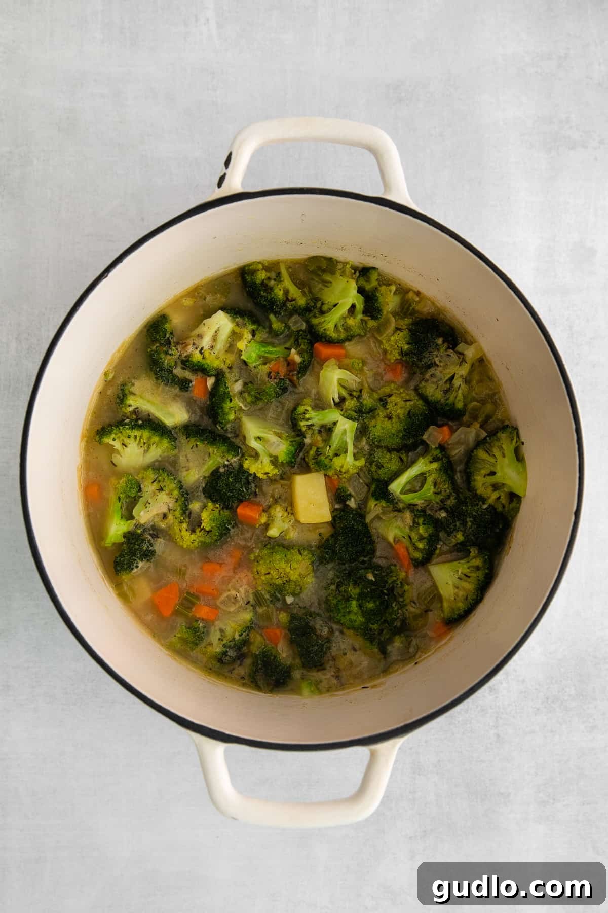 A large pot of vibrant vegetables, including carrots, celery, and onions, simmering gently on the stovetop, releasing their flavors into a savory broth.
