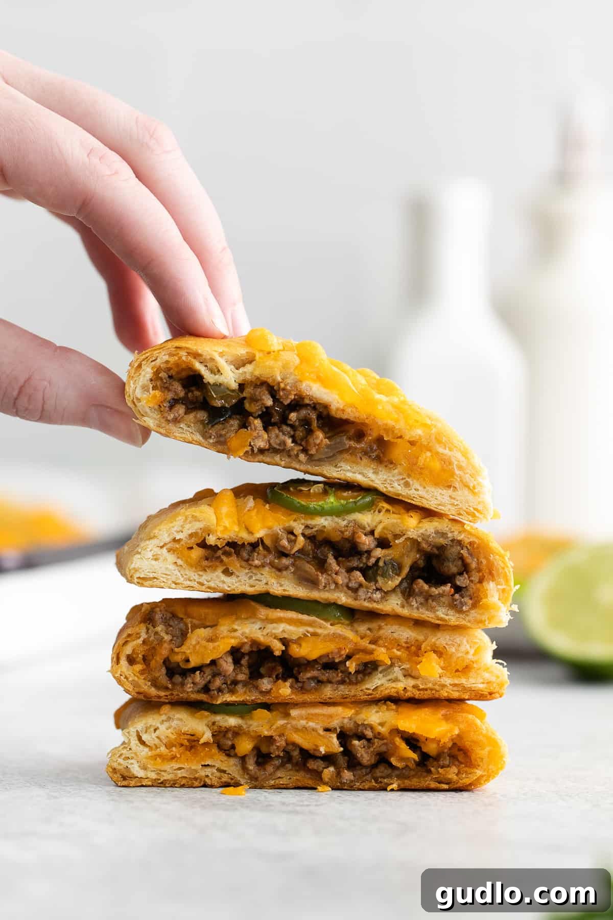 Effortless Taco Pockets 8 A hand reaching for a perfectly golden-brown taco pocket that has been sliced in half, revealing its hearty filling.