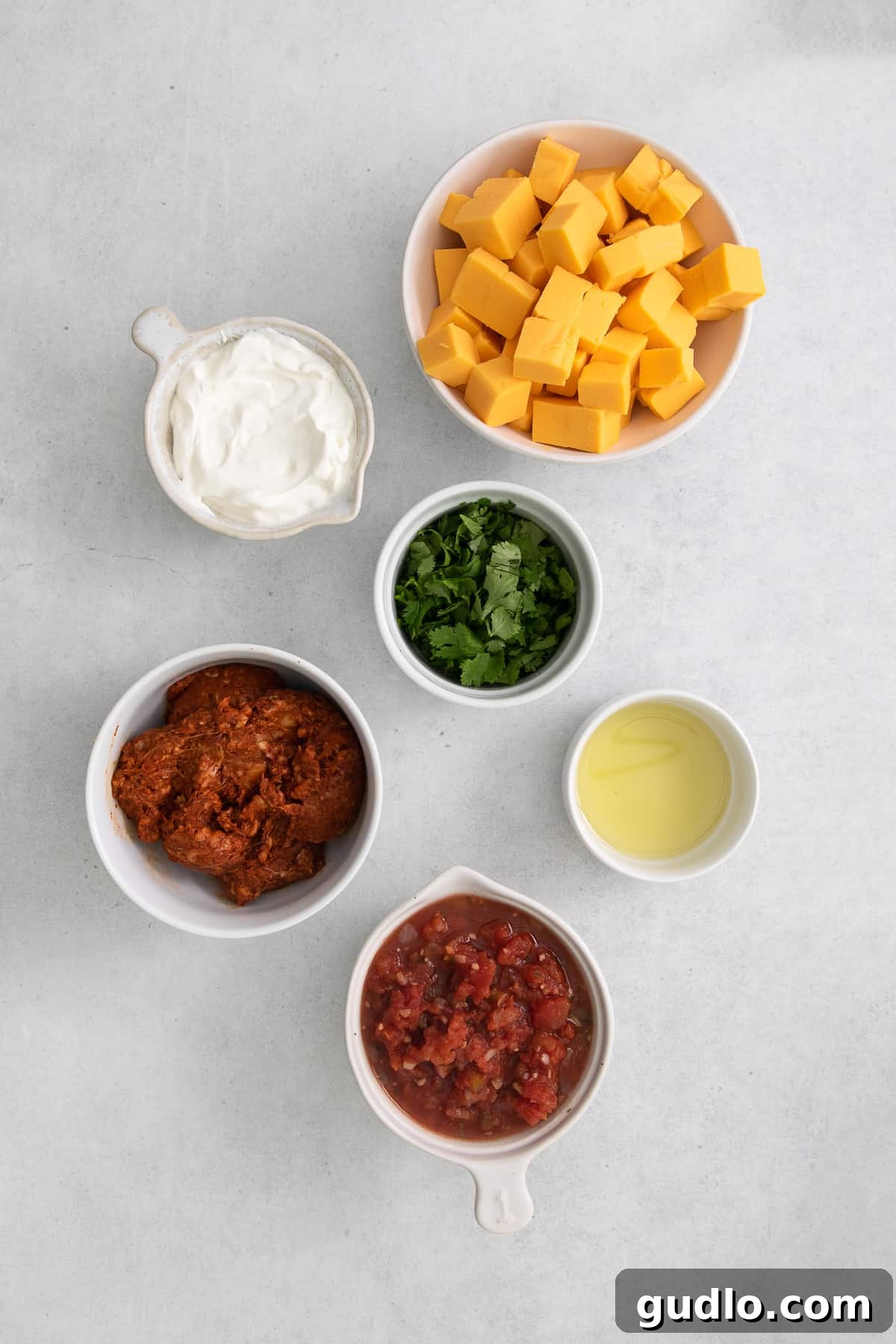 Velveeta Dream Dip 3 A collection of fresh ingredients including Velveeta cheese, ground chorizo, pico de gallo, sour cream, and cilantro laid out on a kitchen counter, ready for preparation.