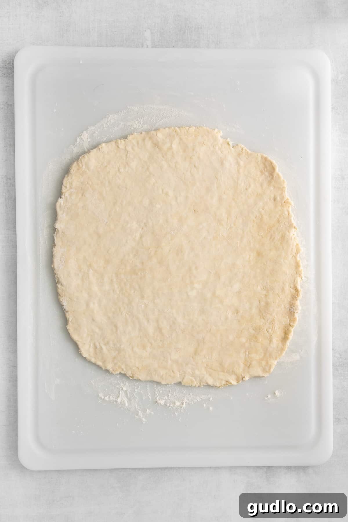 Freshly rolled homemade puff pastry dough, perfectly rectangular and smooth, lying on a wooden cutting board, ready for cutting and shaping into various pastries.