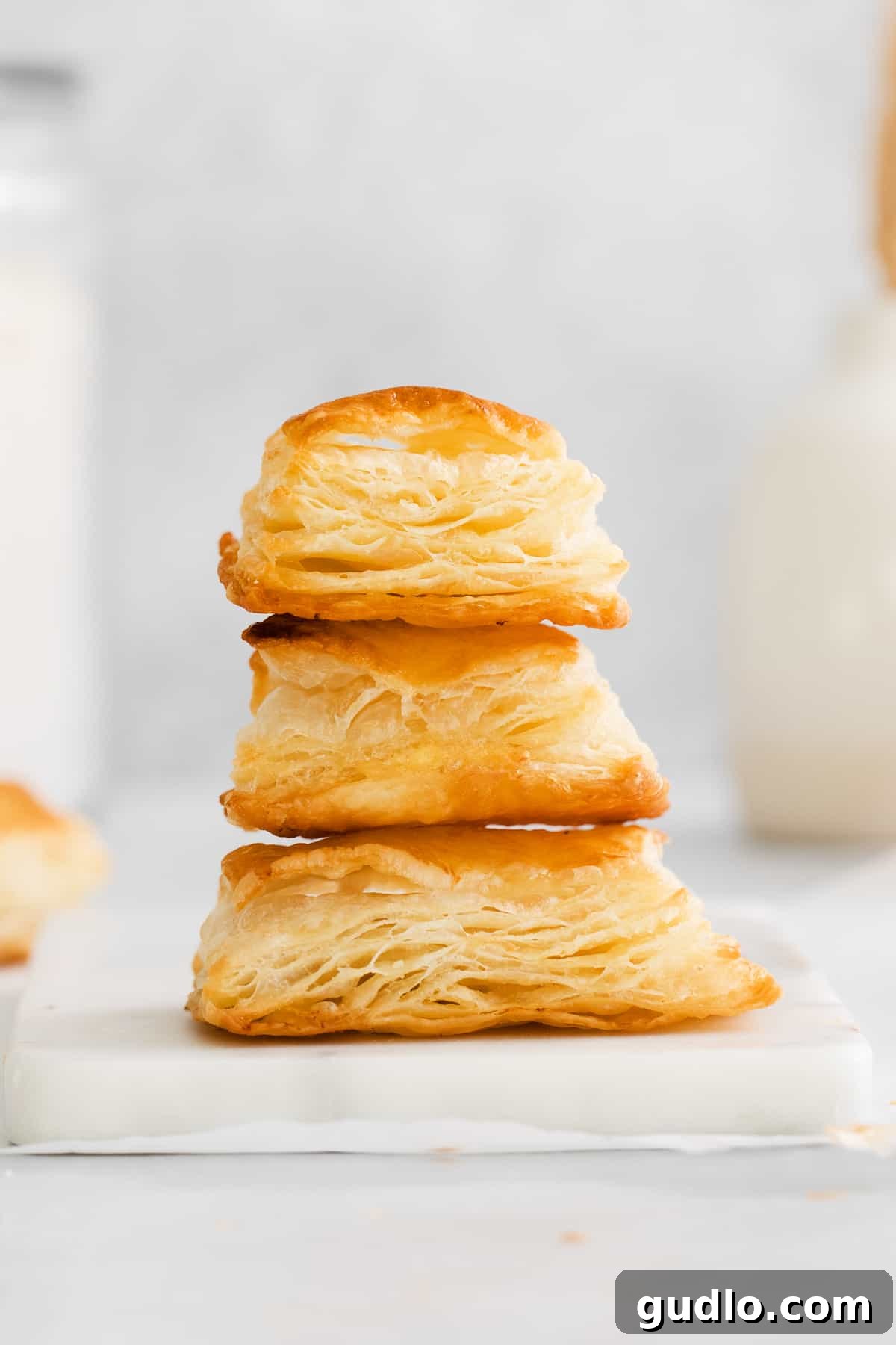 Beautifully baked homemade puff pastry displayed on a wooden cutting board, highlighting its perfectly golden brown color and the visible, enticing flaky layers.