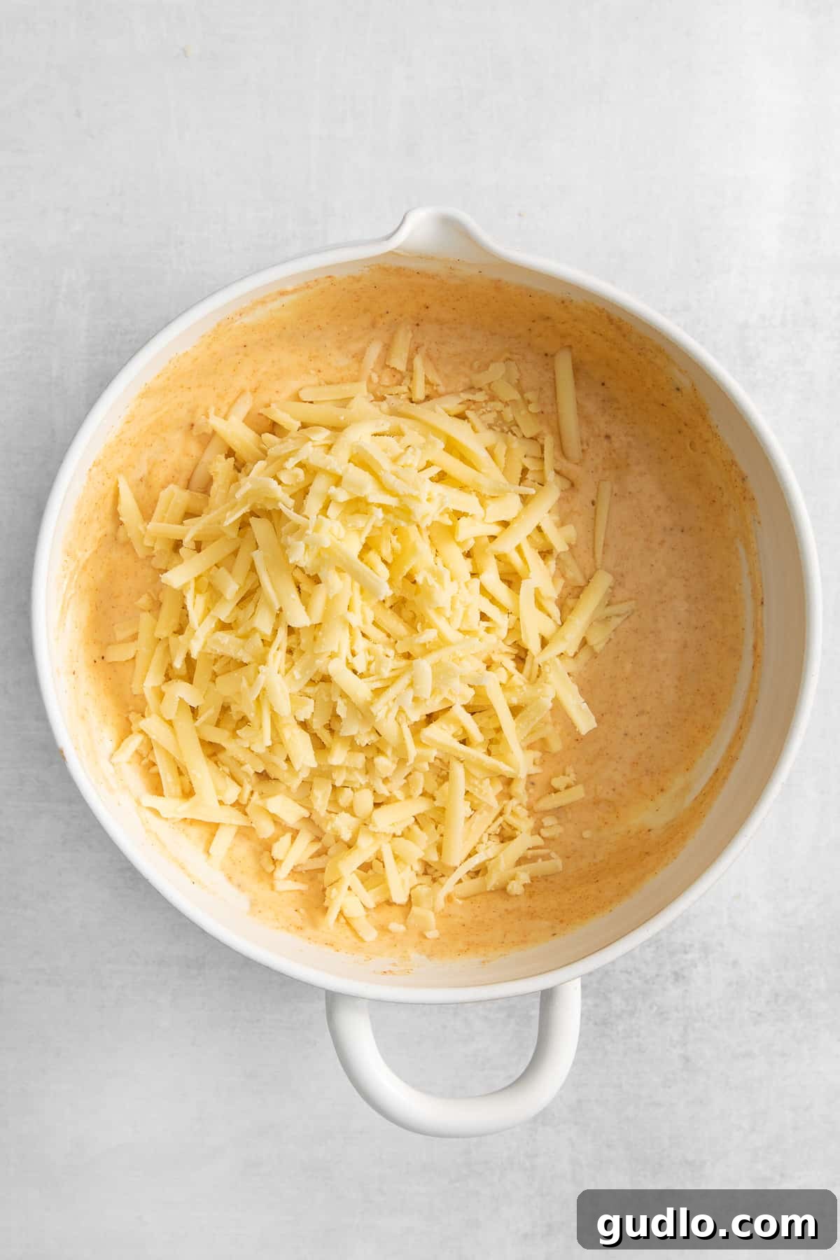 Close-up of shredded Gruyere and Parmesan cheeses in a bowl, ready for the soufflé mixture.