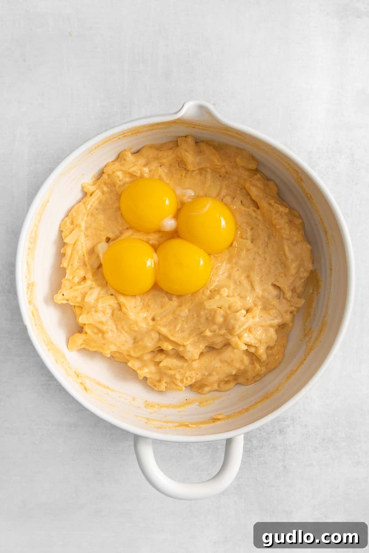 Egg yolks being mixed into a rich cheese soufflé base.