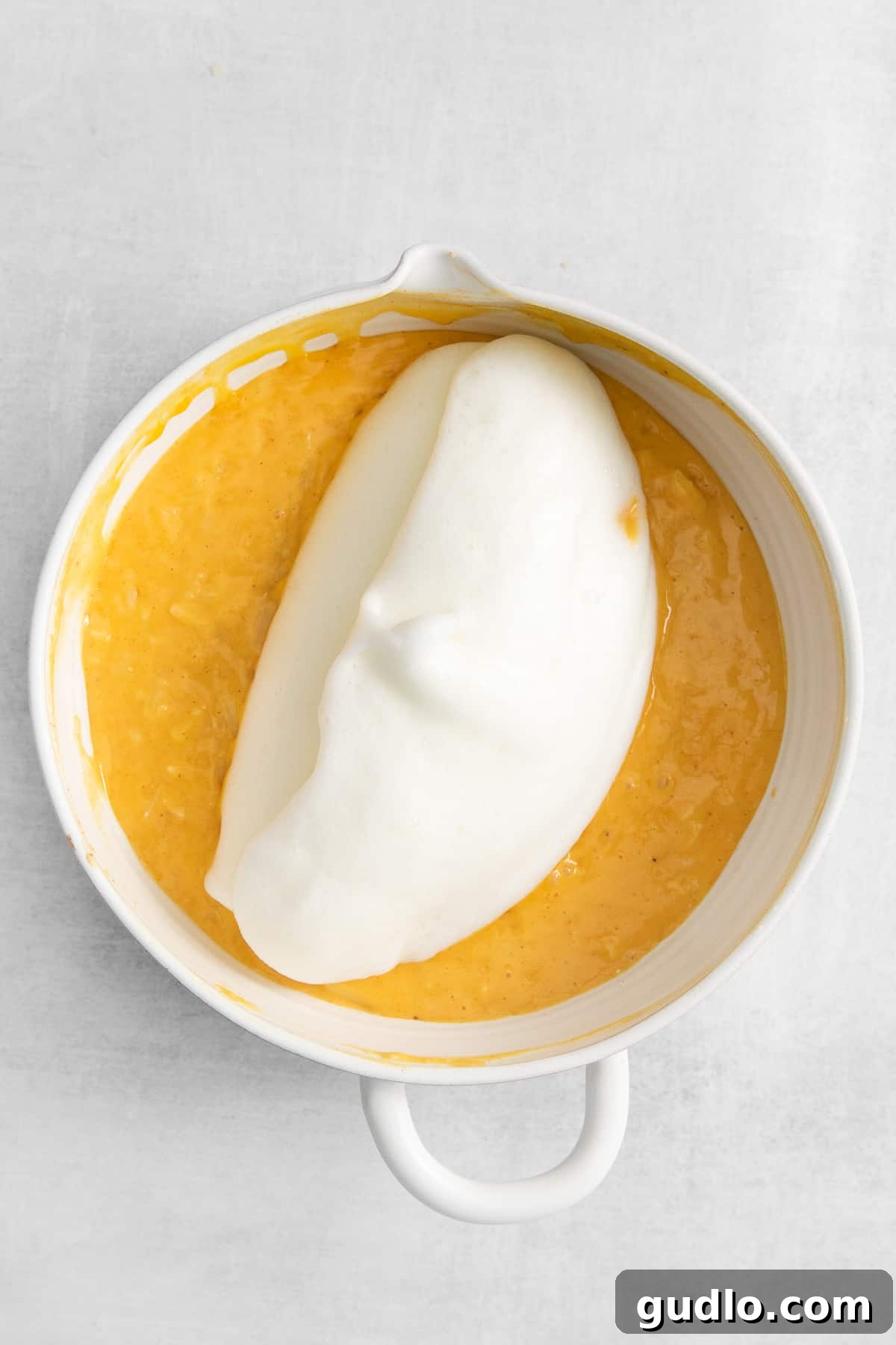 Light and airy whipped egg whites being gently folded into the cheese soufflé mixture.