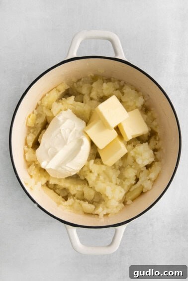 Mashed potatoes with cream cheese and butter added, ready for mixing.