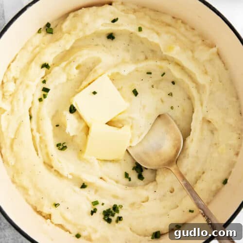 Mashed potatoes in a pot with butter and parsley.