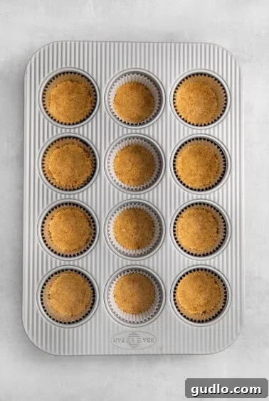 Pressed graham cracker crusts in a mini muffin tin.