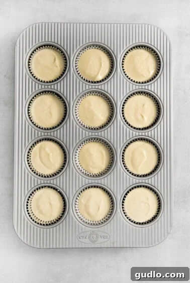 Filling being poured into mini cheesecake crusts.