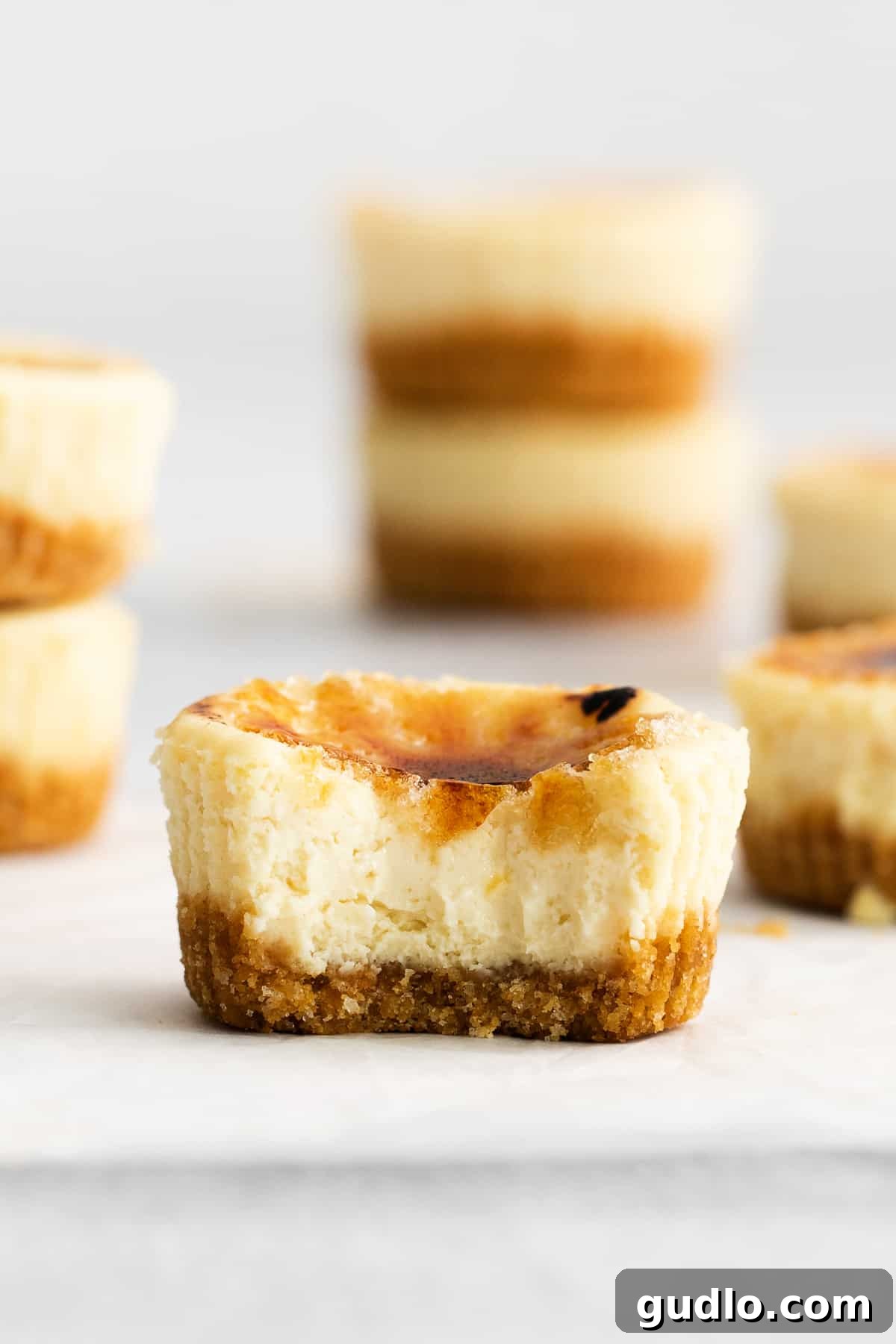 A mini creme brulee cheesecake with a perfect bite taken out, revealing the creamy interior.