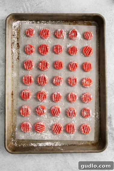 Cream cheese mints being pressed with a fork on a baking sheet.