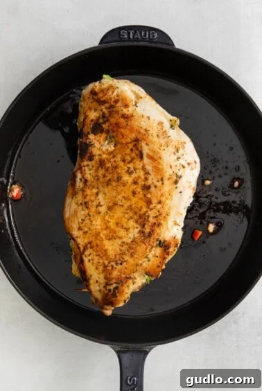 A stuffed turkey breast searing in a cast iron skillet.