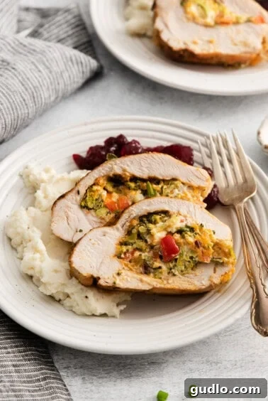 A plate of sliced stuffed turkey breast with vegetables and mashed potatoes, ready to be served.