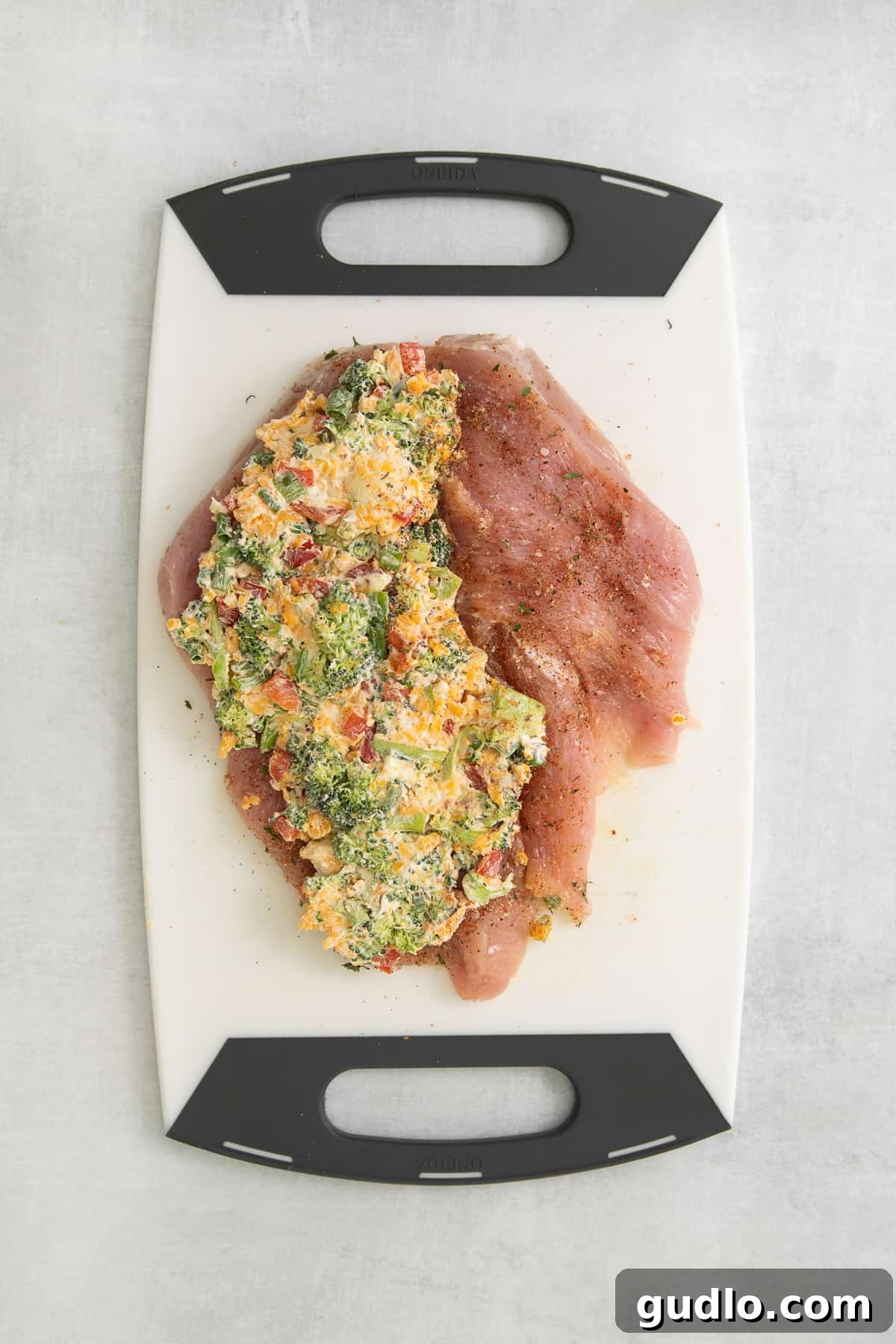 Stuffed Turkey Breast Ready for Cooking Raw turkey breast butterflied open and generously filled with the creamy broccoli and cheese stuffing, secured with toothpicks, on a cutting board, ready for searing.