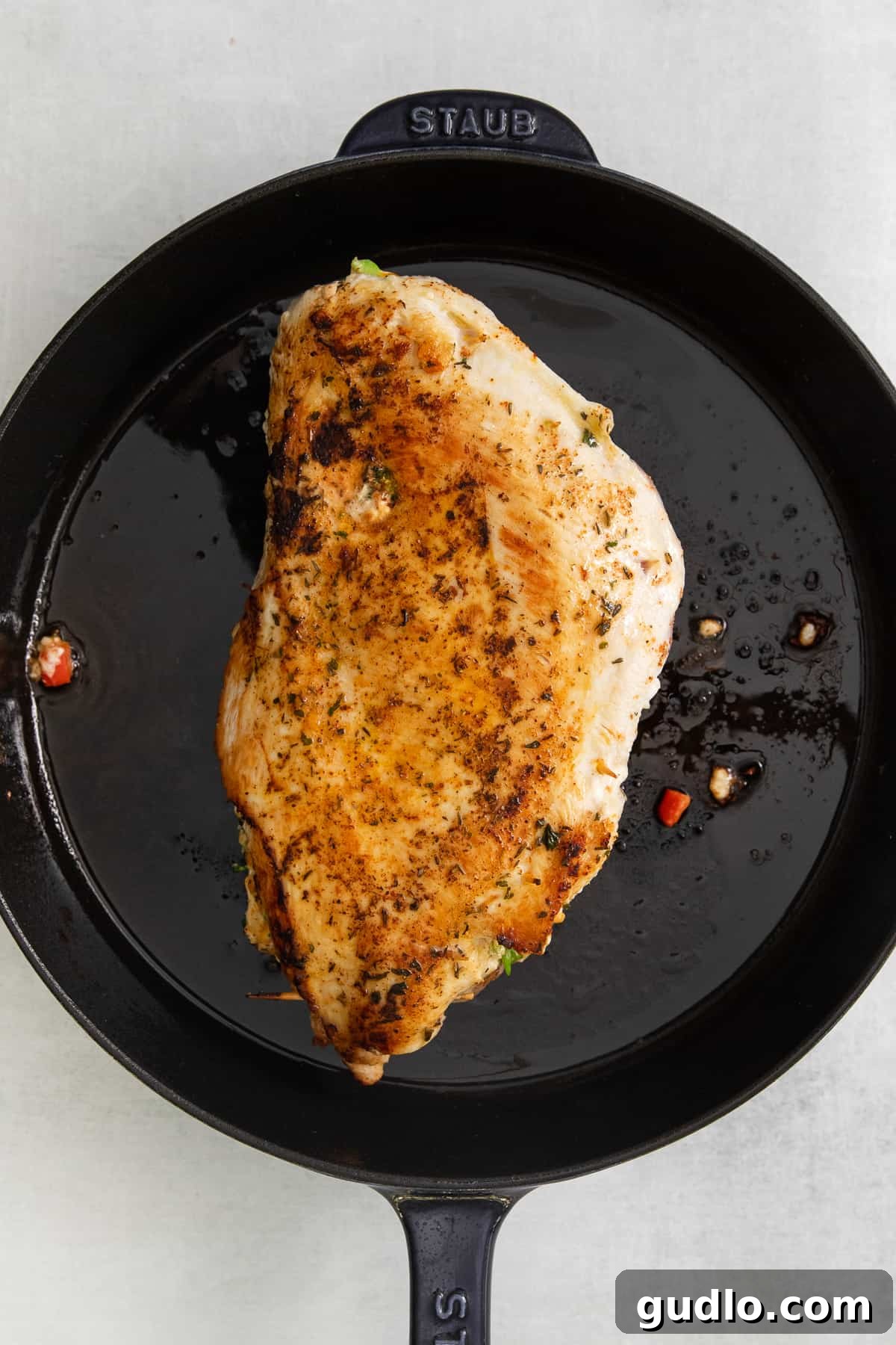 Baked Stuffed Turkey Breast in Skillet The golden-brown stuffed turkey breast resting beautifully in a cast iron skillet, freshly baked and ready to be served.