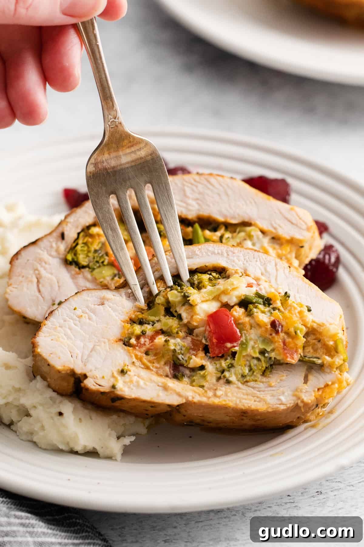 Sliced Stuffed Turkey Breast on Plate A serving of perfectly sliced cheesy broccoli stuffed turkey breast on a plate, garnished and ready to be enjoyed with a side of mashed potatoes.