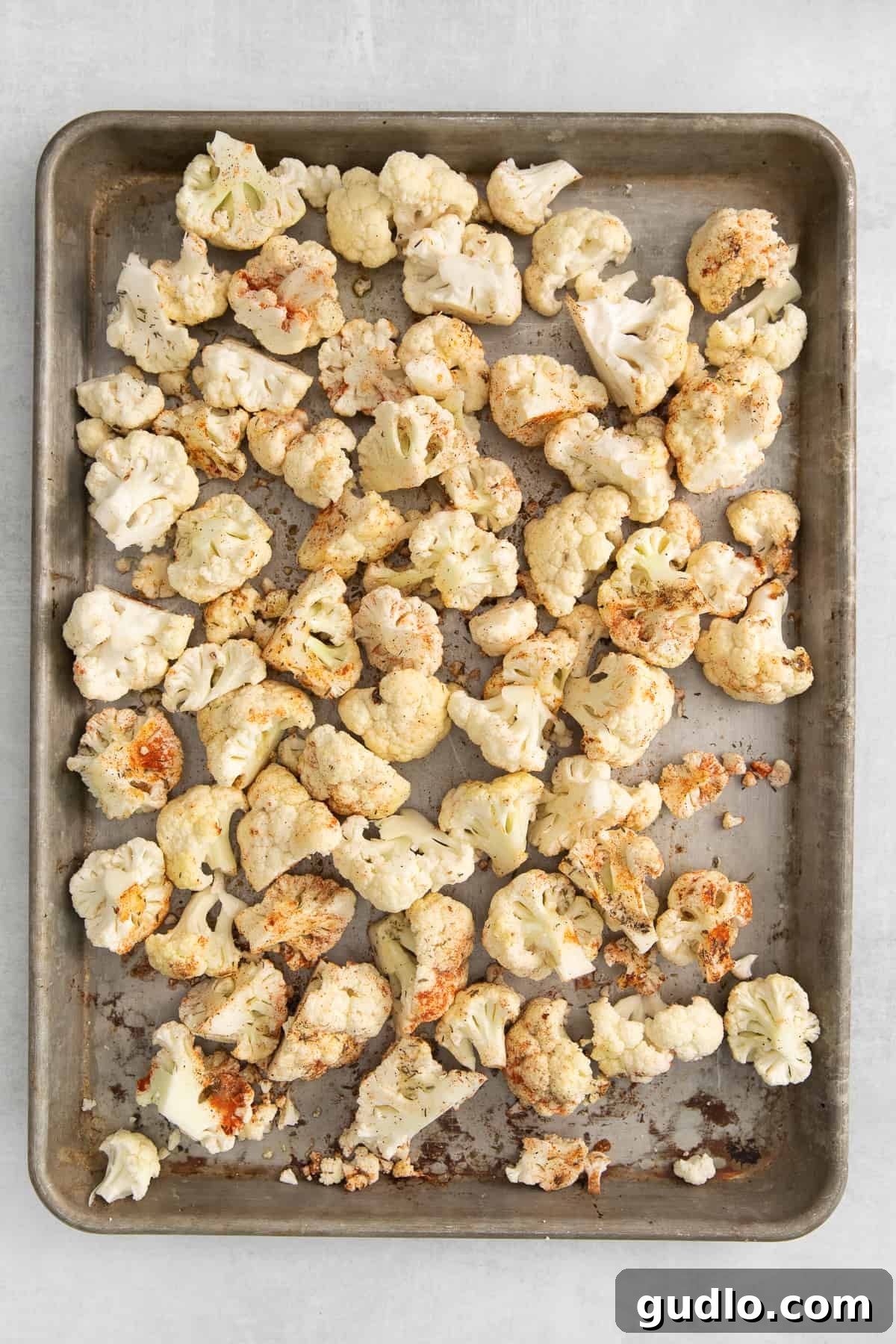 Golden-brown roasted cauliflower florets spread evenly on a baking sheet, fresh from the oven.