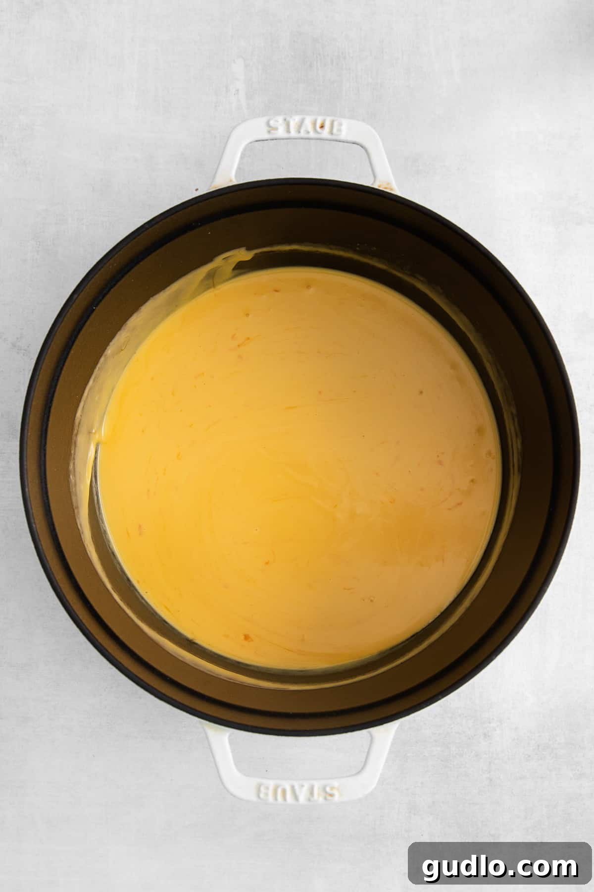Close-up of a rich, creamy mac and cheese sauce simmering in a saucepan.