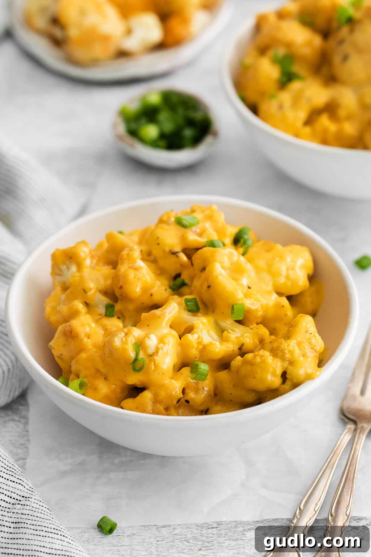 A serving of cauliflower mac and cheese in a rustic ceramic bowl, garnished lightly.