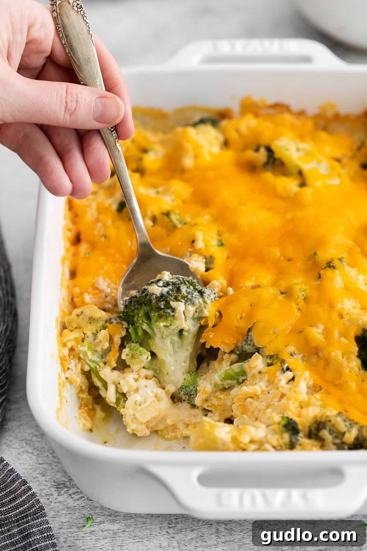 Scoop of broccoli cheese casserole on a spoon, showing creamy texture and broccoli florets.