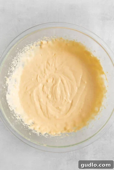 A glass bowl with a yellow batter in it.