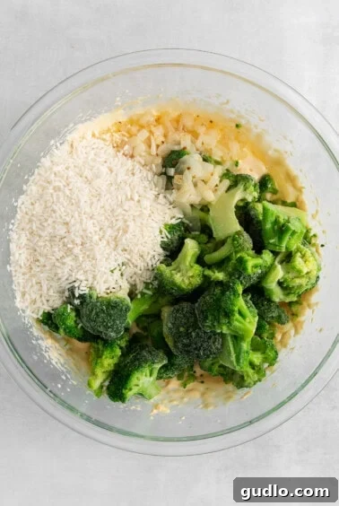 A bowl with broccoli, rice, and cheese sauce in it.