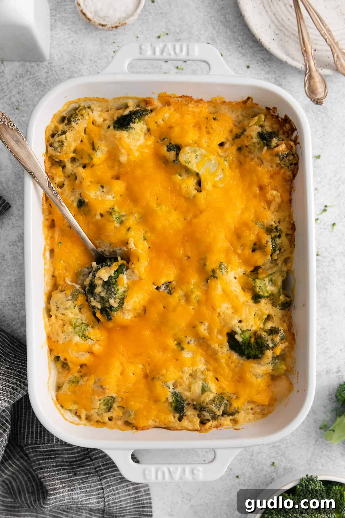 Broccoli cheese casserole topped with melted cheddar cheese in a baking dish.