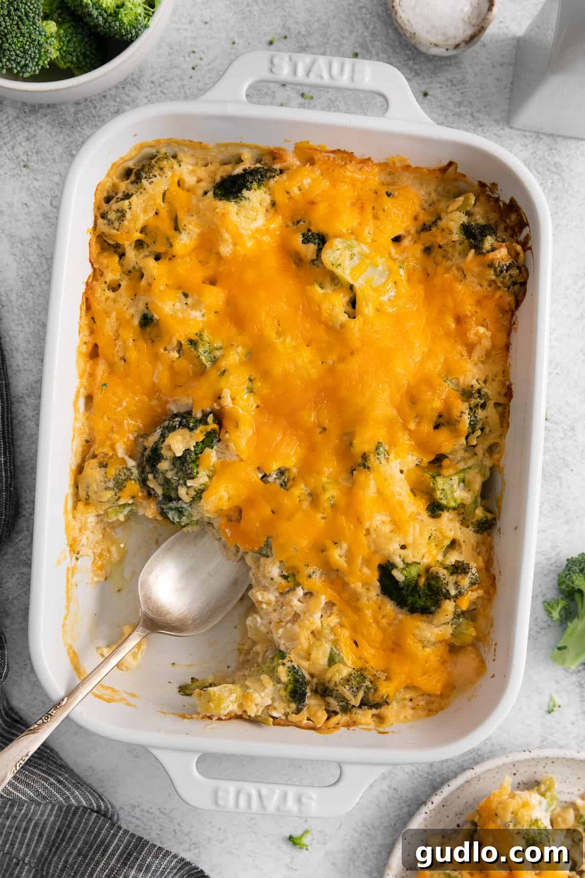 Broccoli cheese casserole in a large ceramic baking dish on a wooden surface.