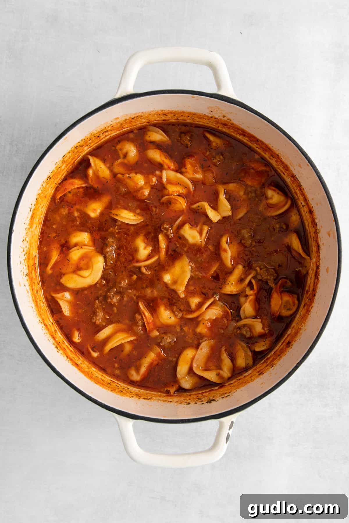 Cheese Tortellini Soup in a Dutch Oven, a true one-pot meal. Cheese tortellini soup simmering in a large red Dutch oven.
