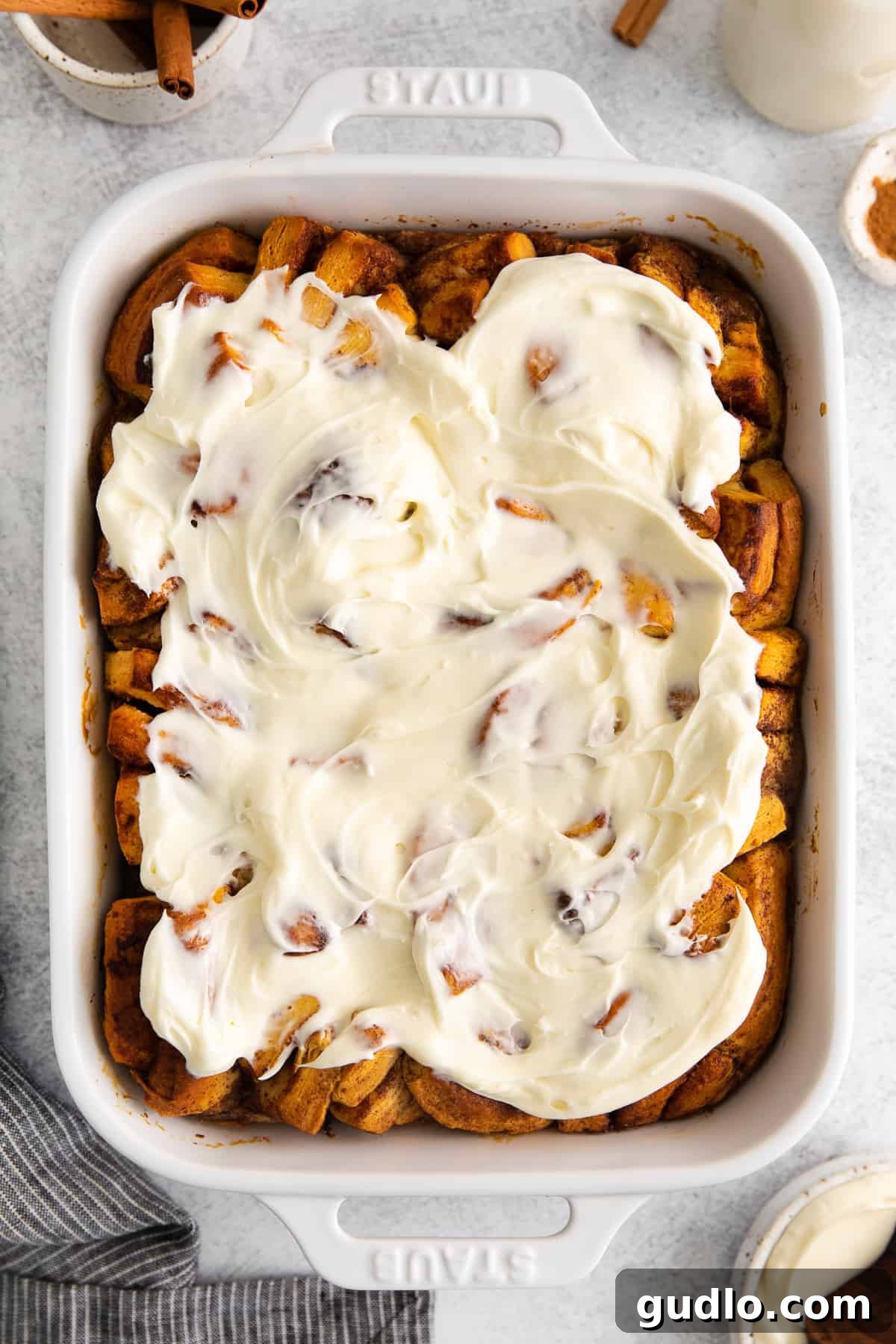 Delicious cinnamon roll casserole with cream cheese icing. Baked cinnamon roll casserole in a dish, generously covered with white icing.