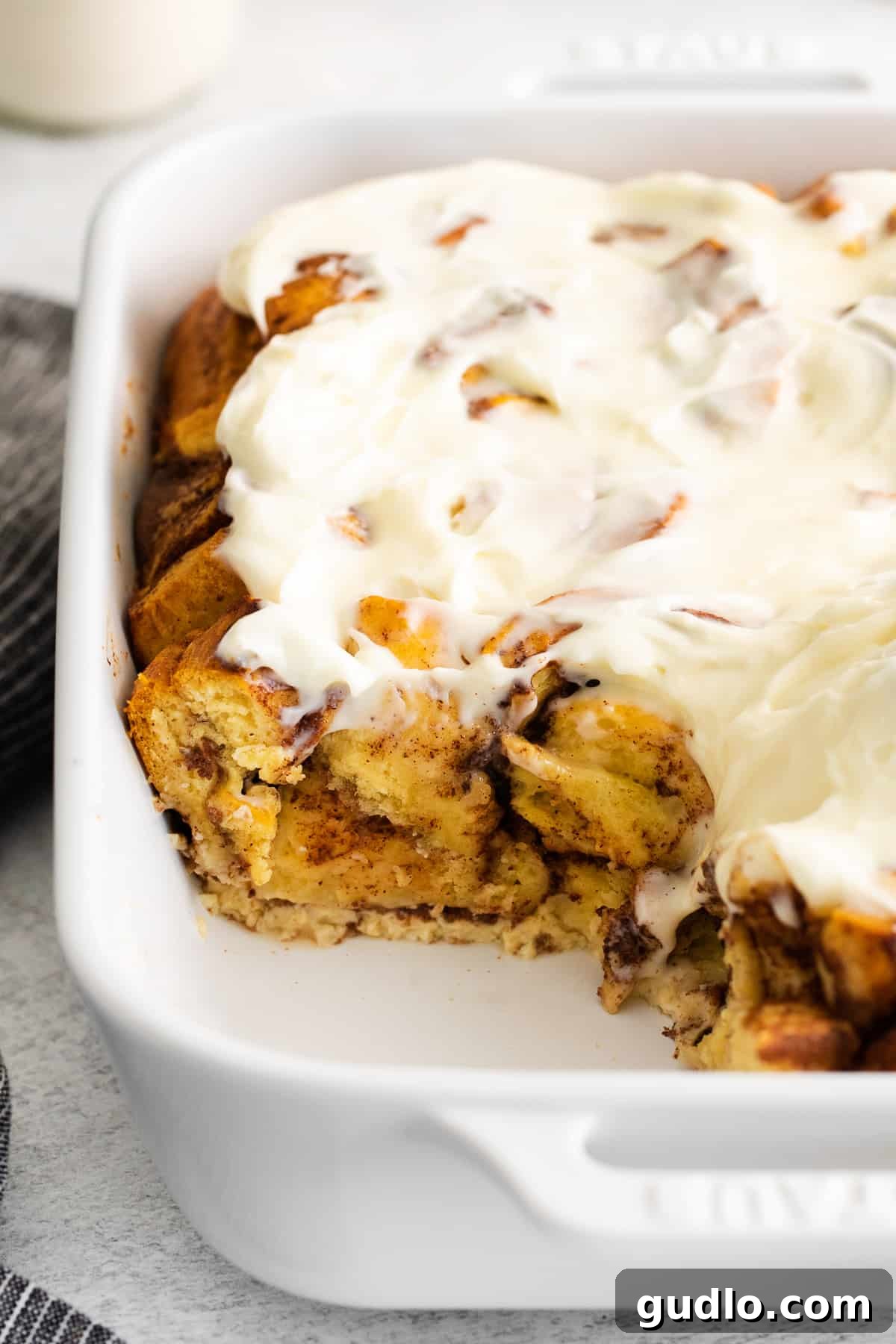 Freshly baked cinnamon roll casserole in a dish. Full cinnamon roll casserole in a white baking dish, fresh from the oven and iced.