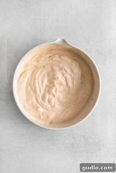 a bowl of creamy sauce on a white surface.