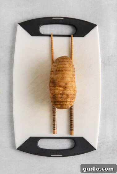 a potato on a cutting board with chopsticks.