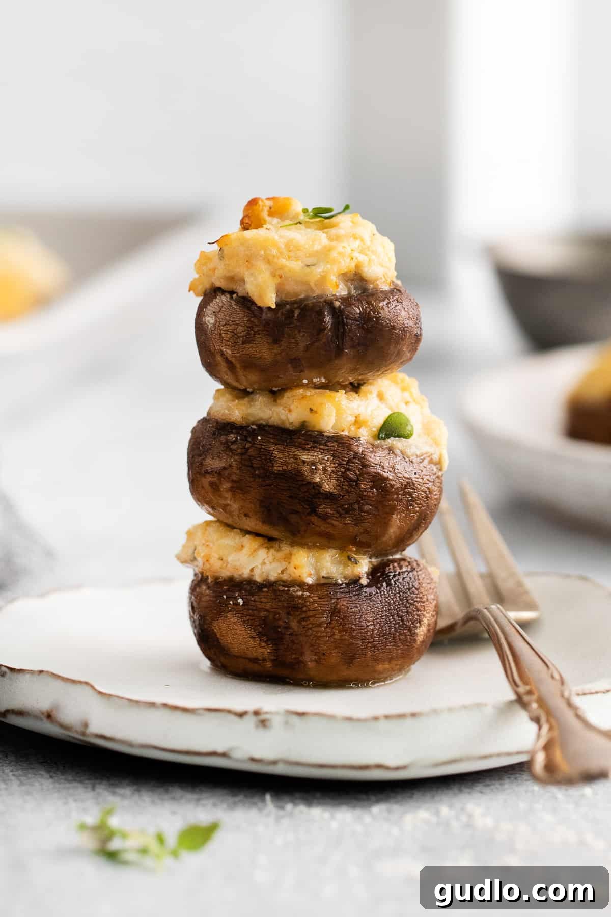 Crab stuffed mushrooms stacked on a plate, garnished with fresh herbs.