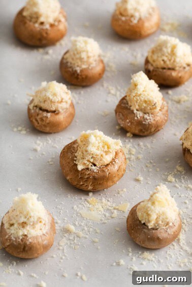 Cheesy stuffed mushrooms arranged on a baking sheet.